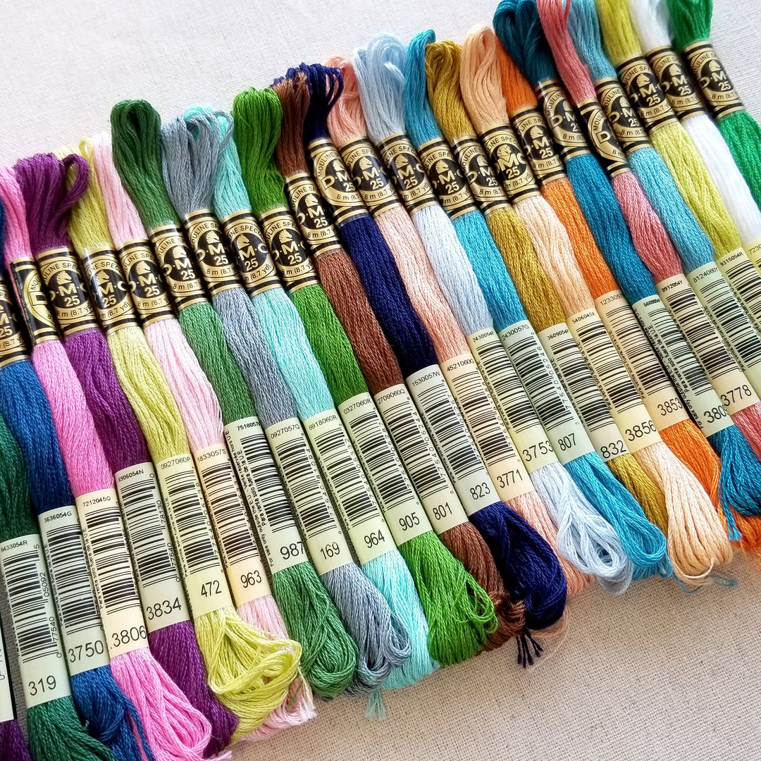 Skeins of hand embroidery floss in assorted colors laying side by side in a long row.